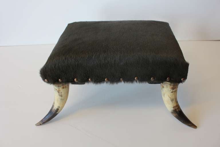 Antique horn based foot stool with cowhide upholstery.