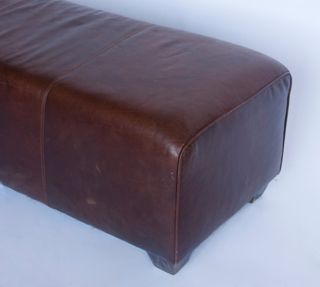 Rustic style long distressed leather bench with wooden legs.