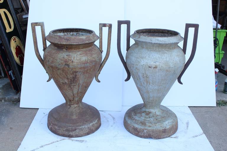 Antique original over sized cast iron Greek style urns/planters.