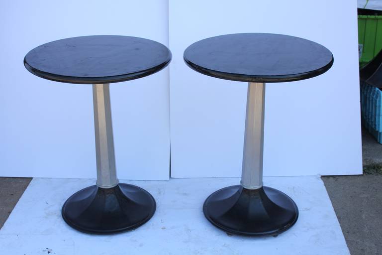 1930s industrial round bistro tables with metal base and ebonized wood top. Two sets available.