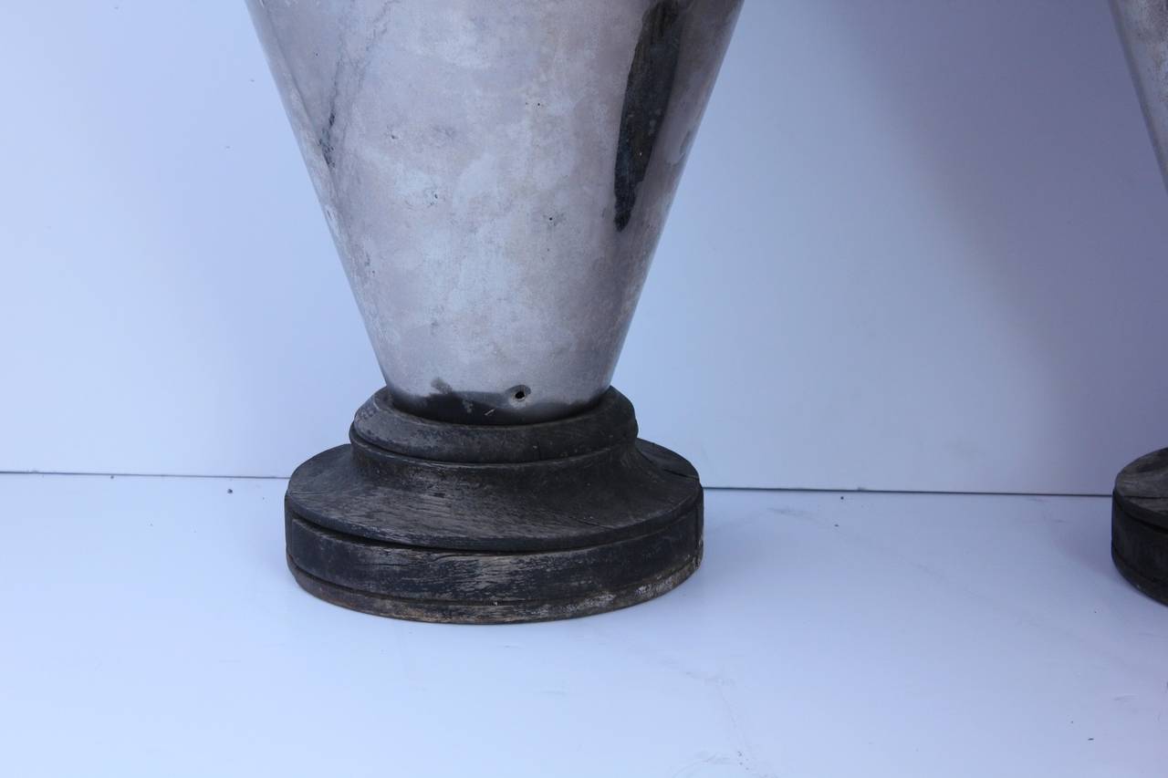 Tall early 20th century stylish metal urns with wooden bases.