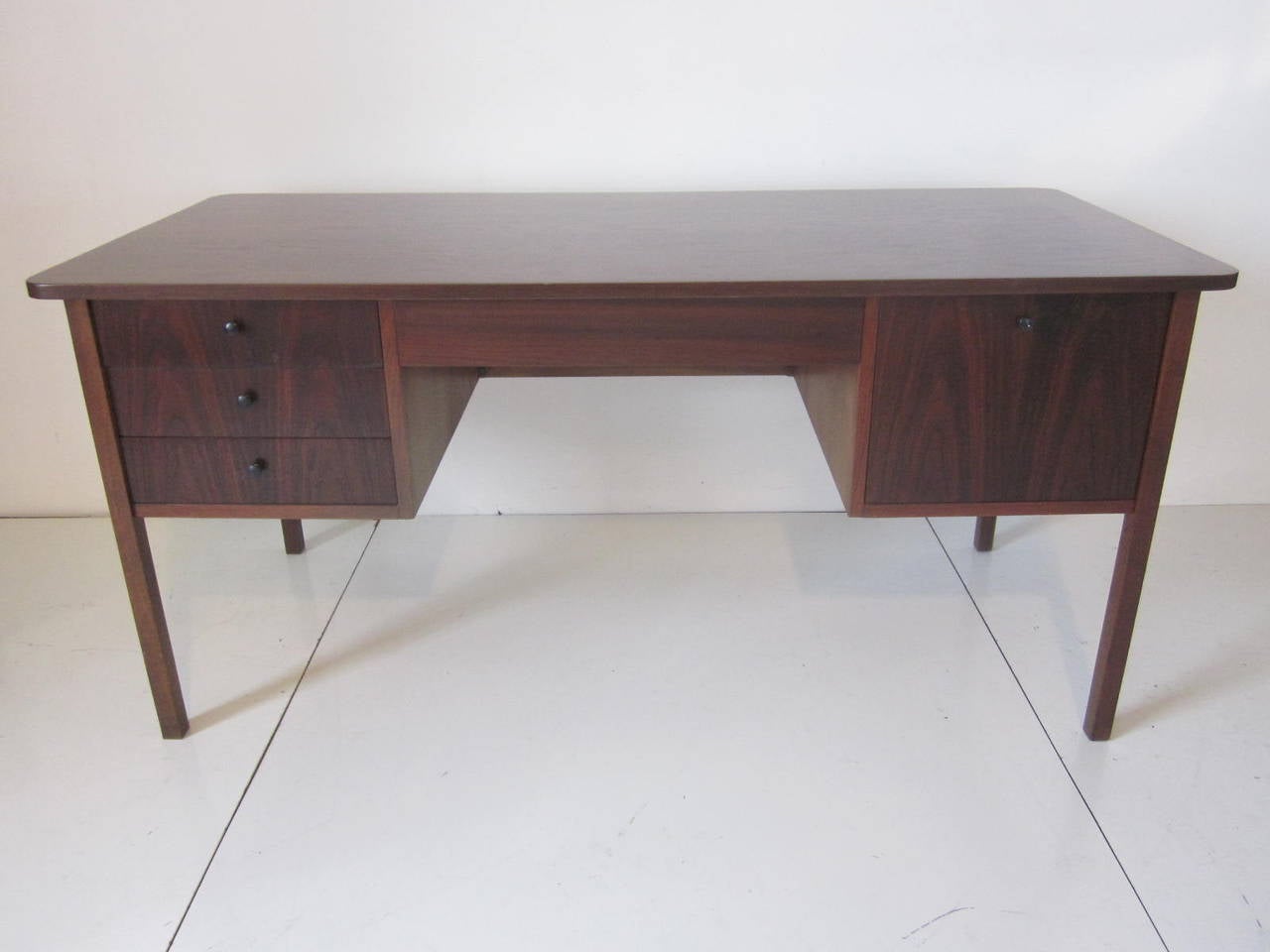 A Danish styled Brazilian rosewood and dark walnut desk with three side drawers, center drawer, large file drawer and a beautifully grained top. On the reversed side is a small caned privacy panel.