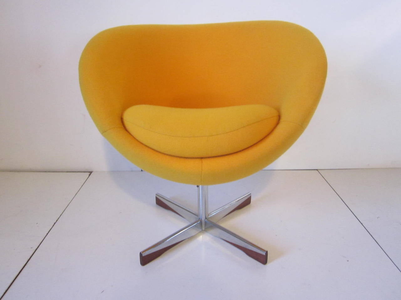 A egg yolk yellow loose seat cushioned upholstered Danish swiveling ball chair with chromed base and walnut details to the X-base, a well-constructed and heavy, just a simple and pure.
Designed piece of furniture.