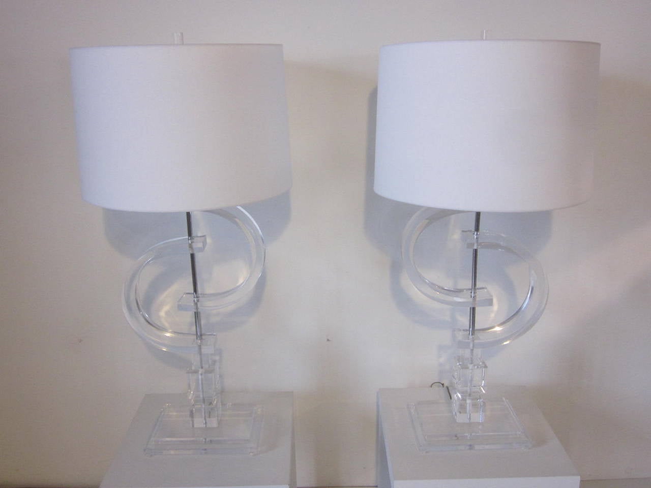 A pair of monumental Lucite table lamps with step up bases, large sculptural pieces mounted on a chromed shaft topped by linen shades and original Lucite finials . These lamp tower above the other Lucite lamps on the market and make a huge statement