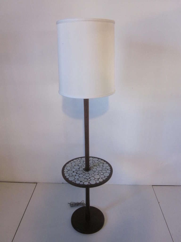 A Danish styled teak wood floor lamp with bone white pottery tiles inset to the  table top and matching teak wood finial and base.Manufactured by Marshal Studios