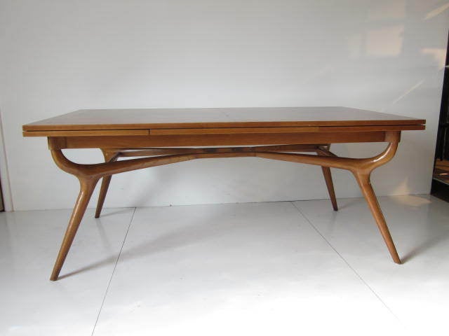A sculptural dining table with build in leaf extentions to each end sitting on carved curved legs and strechers.Designed by Harold Schwartz a native of Pittsburgh who traveled to attend the New York School of Applied Fine Arts.After his education he