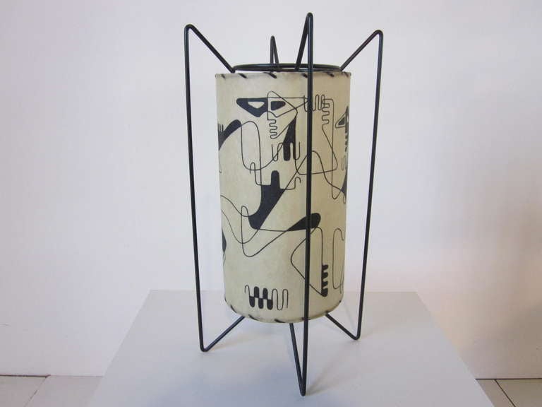 A rare Weinberg parchment table lamp with Picasso styled figures circling the shade, sitting on a bent black metal wire frame. Signed printed in the shade by the artist.