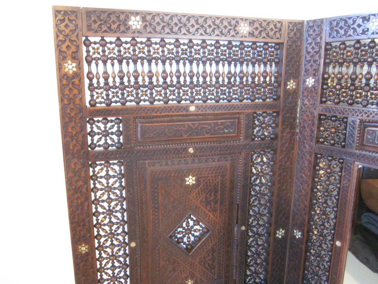 A three-panel Moroccan room divider with turned and carved wood details, ivory like inlay and mirror. From the estate of a noted Cincinnati architect bought in the east and retains the tag from their ownership in the 1960s.