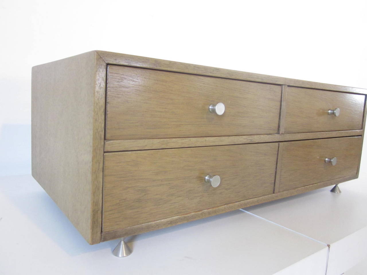 A three-drawer Mid-Century jewelry chest with stainless pulls and matching hour glass legs, bottom drawer has a adjustable divider.