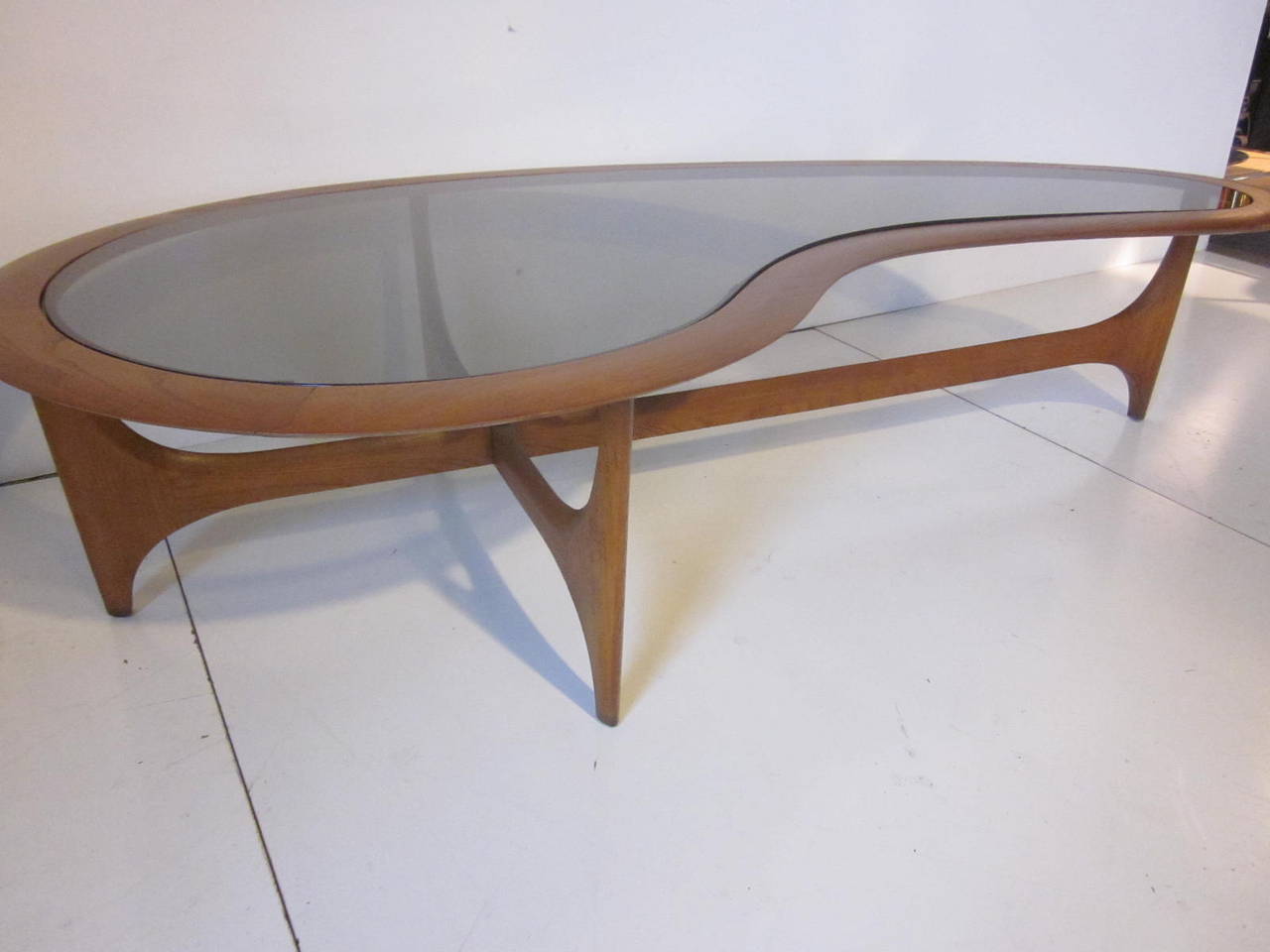 A sculptural wood coffee table with a kidney shape slightly tinted glass top insert. Nice interesting legs in the style of Vladimir Kagan manufactured by the Lane Furniture Company.