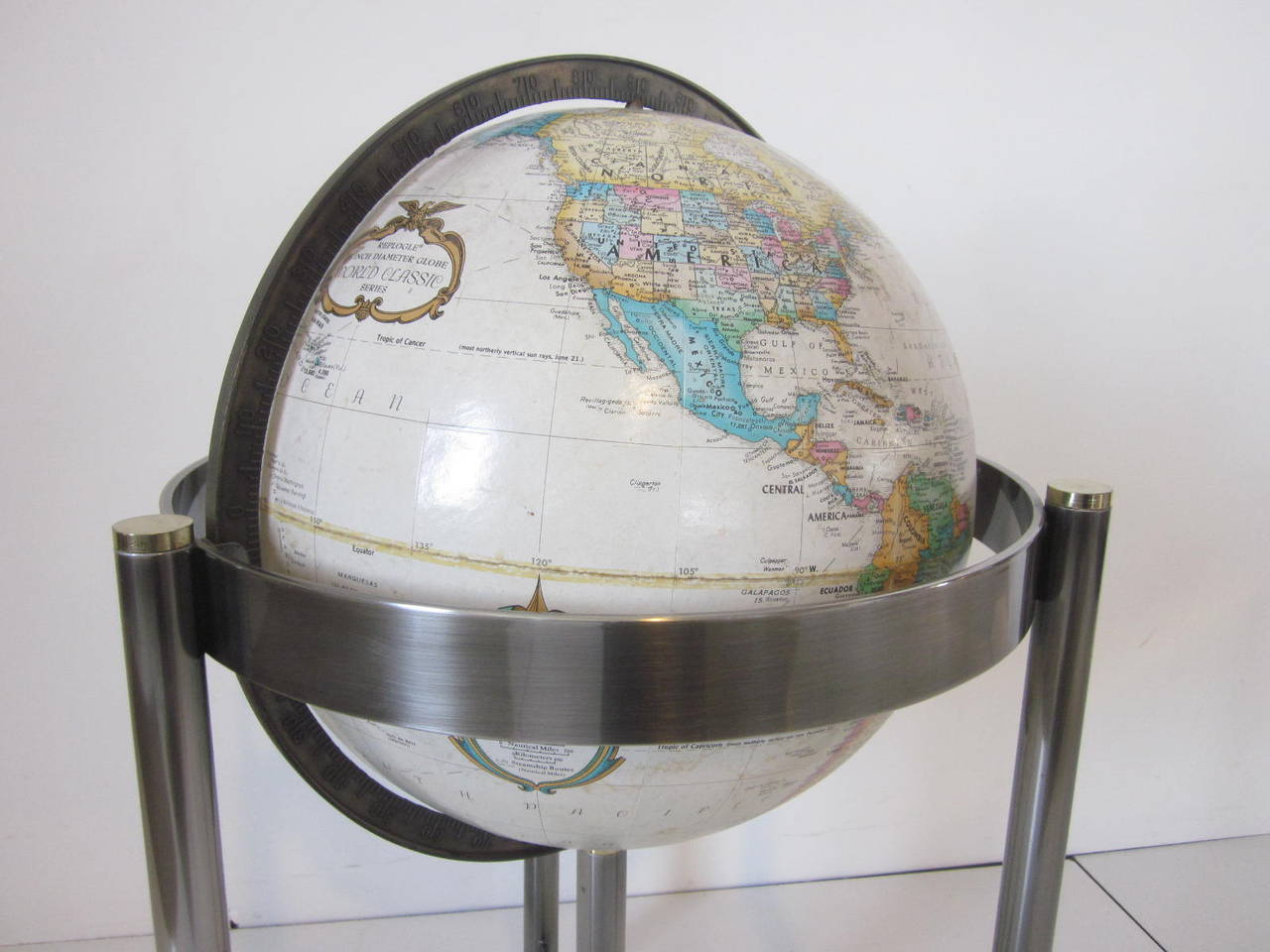 A brushed satin stainless steel floor globe with brass accented pieces and lighter colored globe giving this a sophisticated modern and clean design asthenic. Manufactured by the Replogle company.