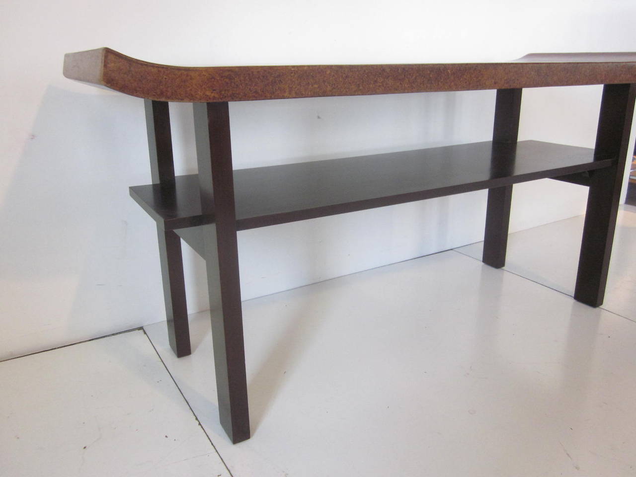 A rare and hard to find Frankl cork topped console or serving table with dark ebony colored mahogany base with shelve and upturned edged top. Manufactured by the Johnson Brothers Furniture Company.