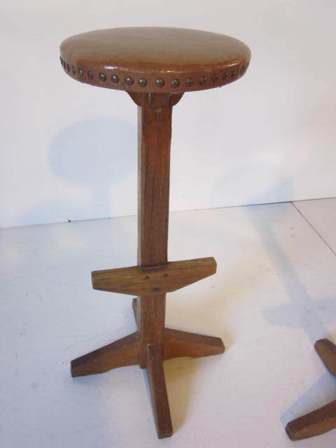 A pair of Ranch Oak bar stools with vinyl seat and detailed brass studs and foot rests.