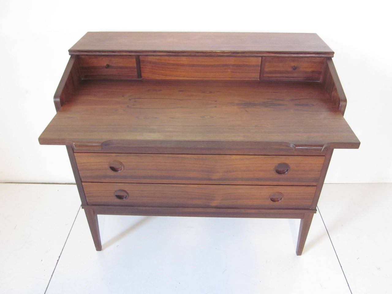 A richly grained Brazilian rosewood desk with pull-out desk top, three large lower drawers and two upper small drawers. Nice rounded integrated pulls to the drawer fronts, making this small scaled desk perfect for a tight location. Manufactures