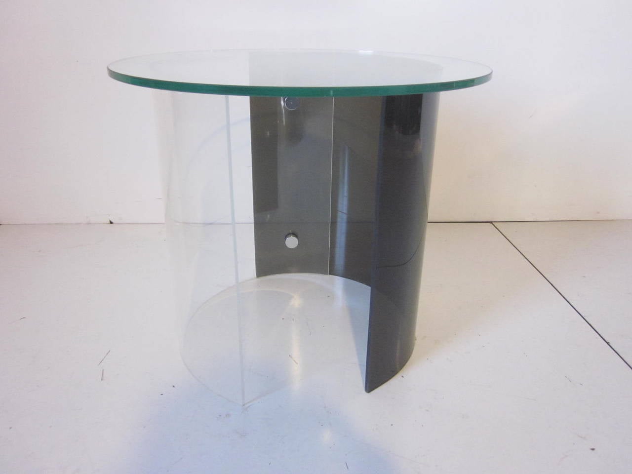 A Lucite glass topped side table with smoked and clear Lucite joined to form a near circle with chromed knob styled screws holding them together, in the style of Charles Hollis Jones and Neal Smalls.
