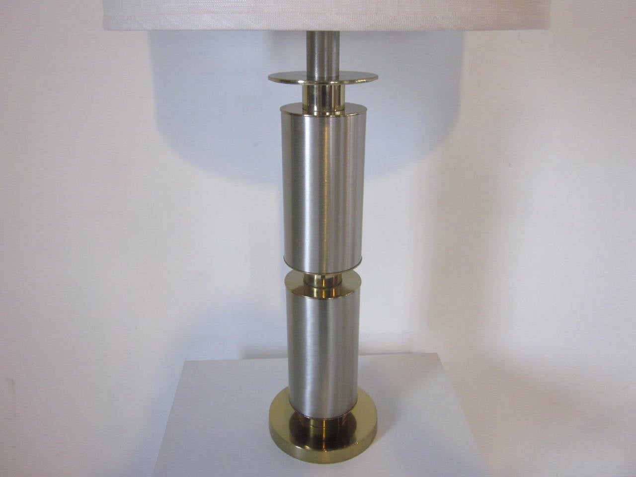 A brushed stainless and brass table lamp with linen shade manufactured by the Laurel Lamp Company.