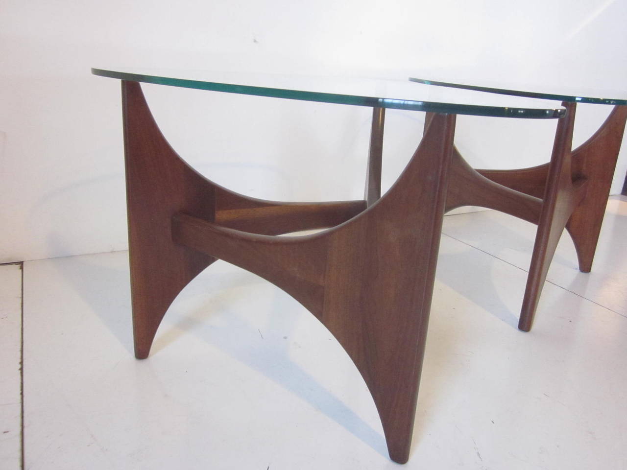 A matching pair of solid walnut sculptural side tables with triangle-shaped glass tops manufactured by Craft Associates.