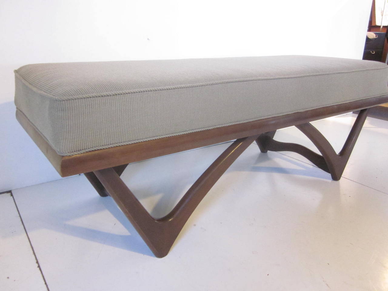 A sculptural wood based bench in the manner of Adrian Pearsall with upholstered cushion.