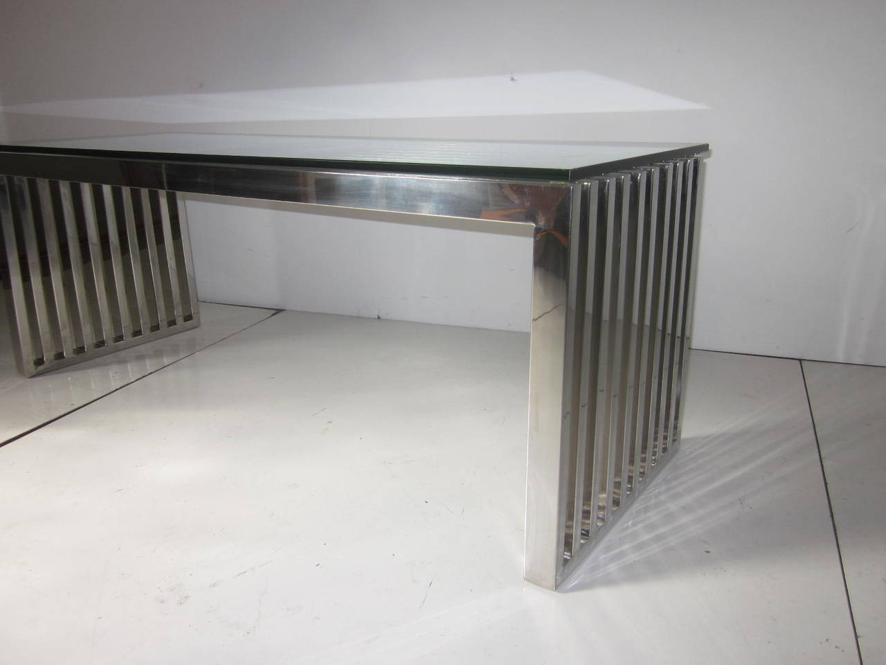 A chromed metal slated plate glass topped coffee table with fine detailed workmanship ,a great and simple design .