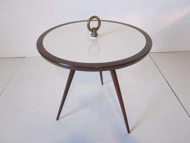 A Mid Century mahogany tri pod based side table with brass ring detail and a off white laminate insert to the table top.