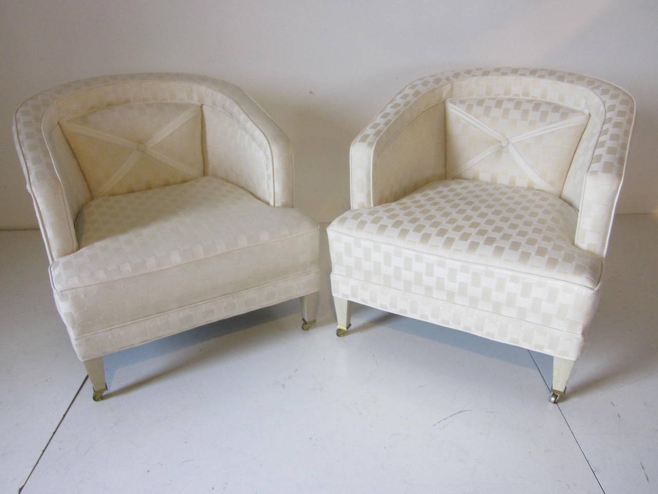 A pair of lounge chairs in the manner of Grosfeld House with front bass caster tipped legs and great rear X leg design. Well-made with springs to the bottom and with matching X ribbon upholstered detail to the built in back cushion and with