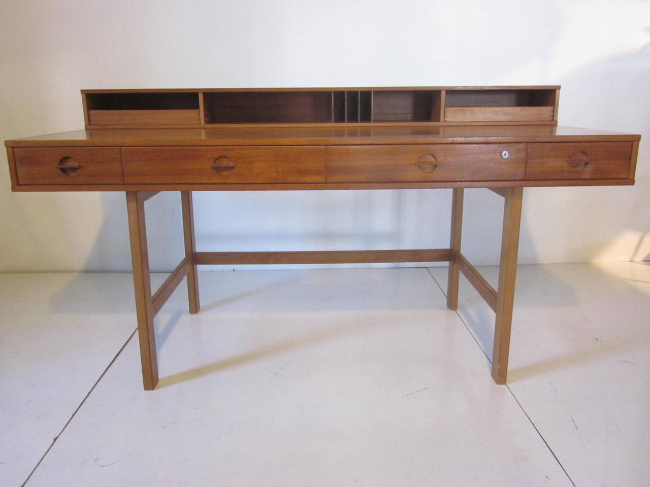 A teakwood folding file top desk with many cubbies with two drawers and four drawers to the front, the back side has a bit of storage also, sitting on removable legs for ease of moving and set up. The best part of this design is that the file area