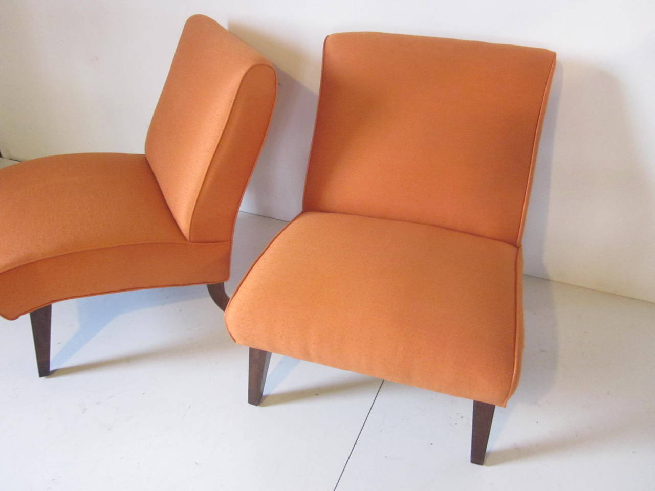 A pair of slipper chairs upholstered in a melon colored raw silk with mahogany legs in the style of Grosfeld House and designer Lorin Jackson.