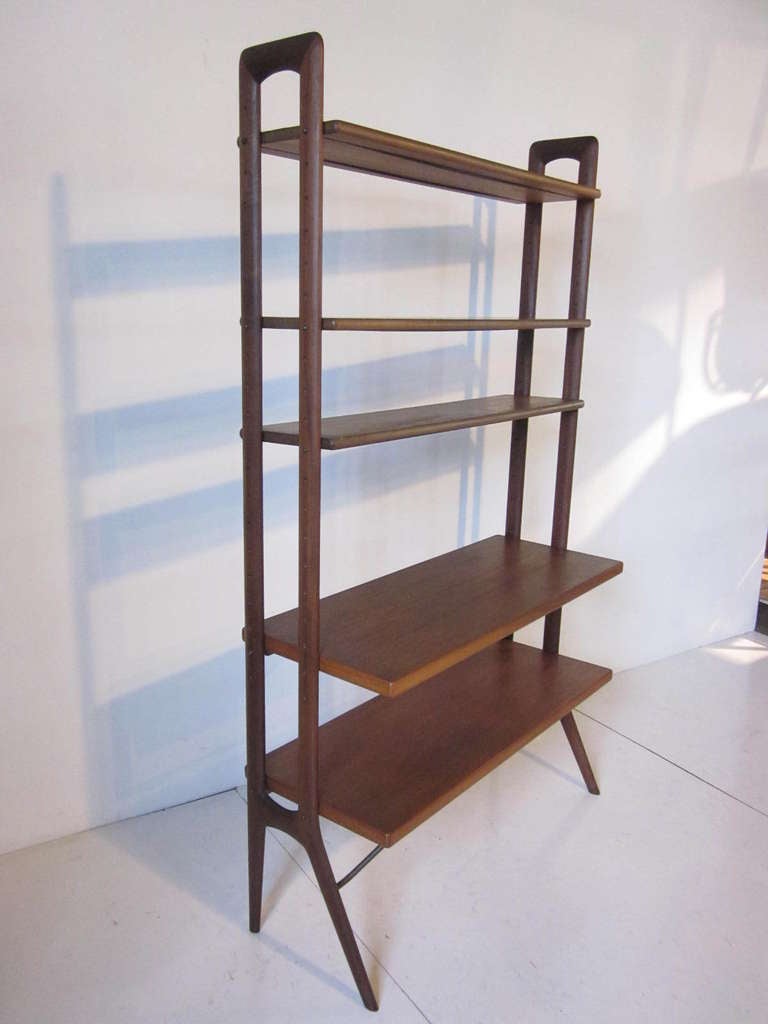 A teak and rosewood unit with five adjustable teak shelves,two larger and three smaller sized ,metal lower architectural braces and metal rods and screw system to hold the shelves into place. A well thought out design that's made in Denmark by KP