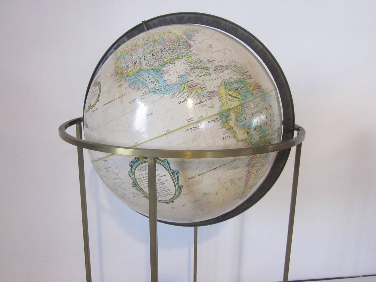 A brass square tubed framed floor globe with tilting and turning Stand and world globe made by Replogle.