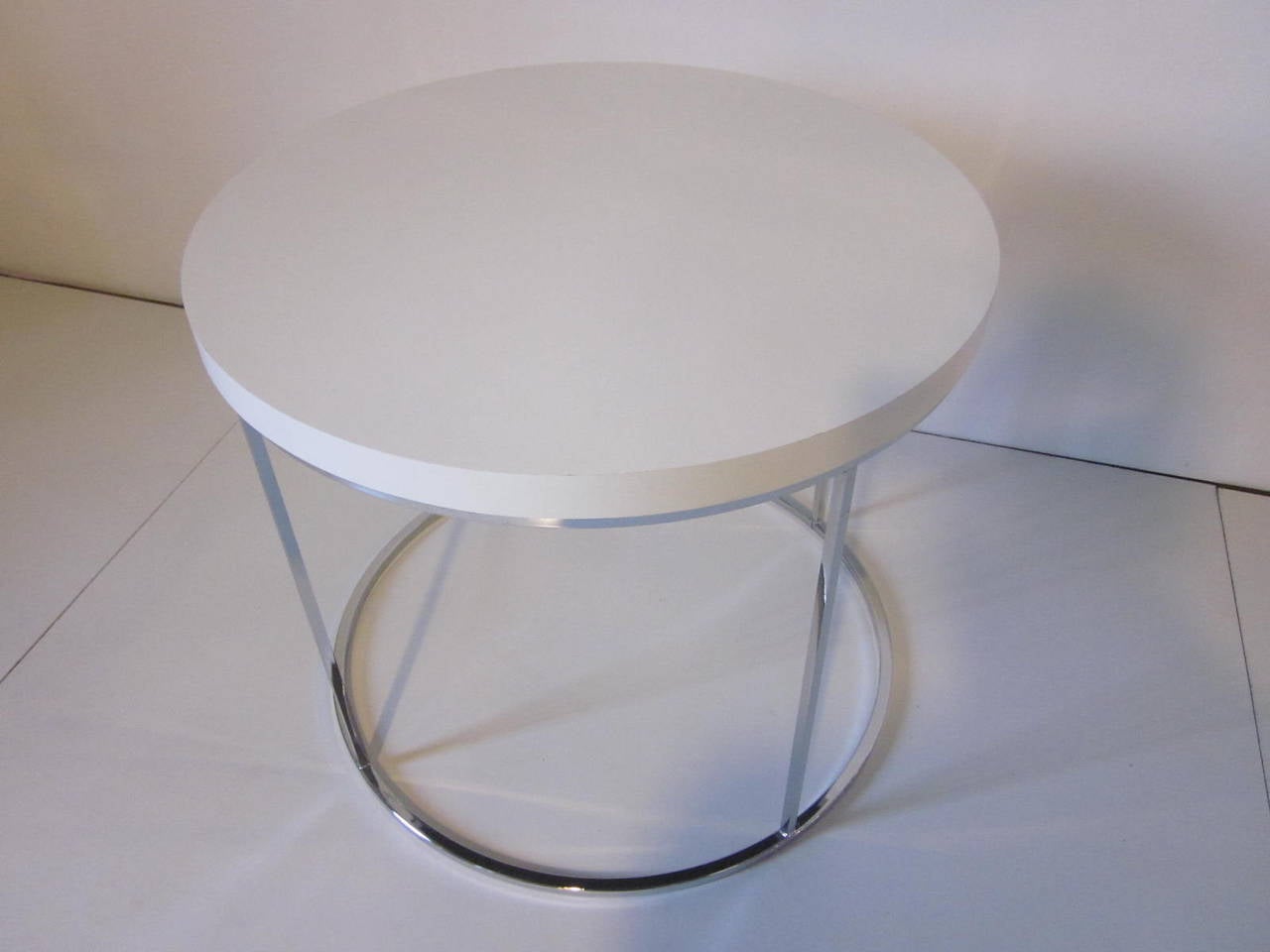 A chromed square tubed side table with a white laminate top manufactured by Thayer Coggin.