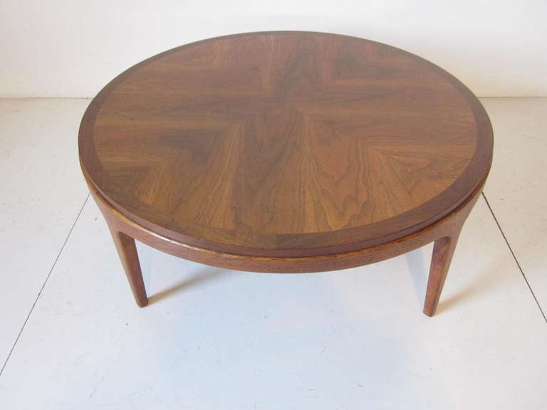 A book matched walnut topped round Mid Century coffee table with smooth detail joinery that flow into the four legs. Manufactured by the Lane Furniture Company. 