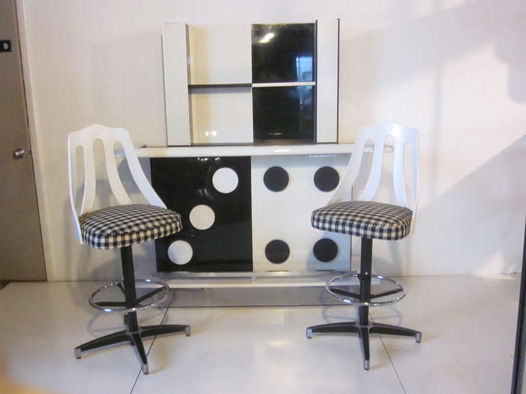 This wild Domino styled bar with two matching stools and light up hanging back bar is upholstered in Patten leather like vinyl with painted  surfaces, Formica and an aluminum foot rest. The bar stool backs are white fiberglass , the stools swivel