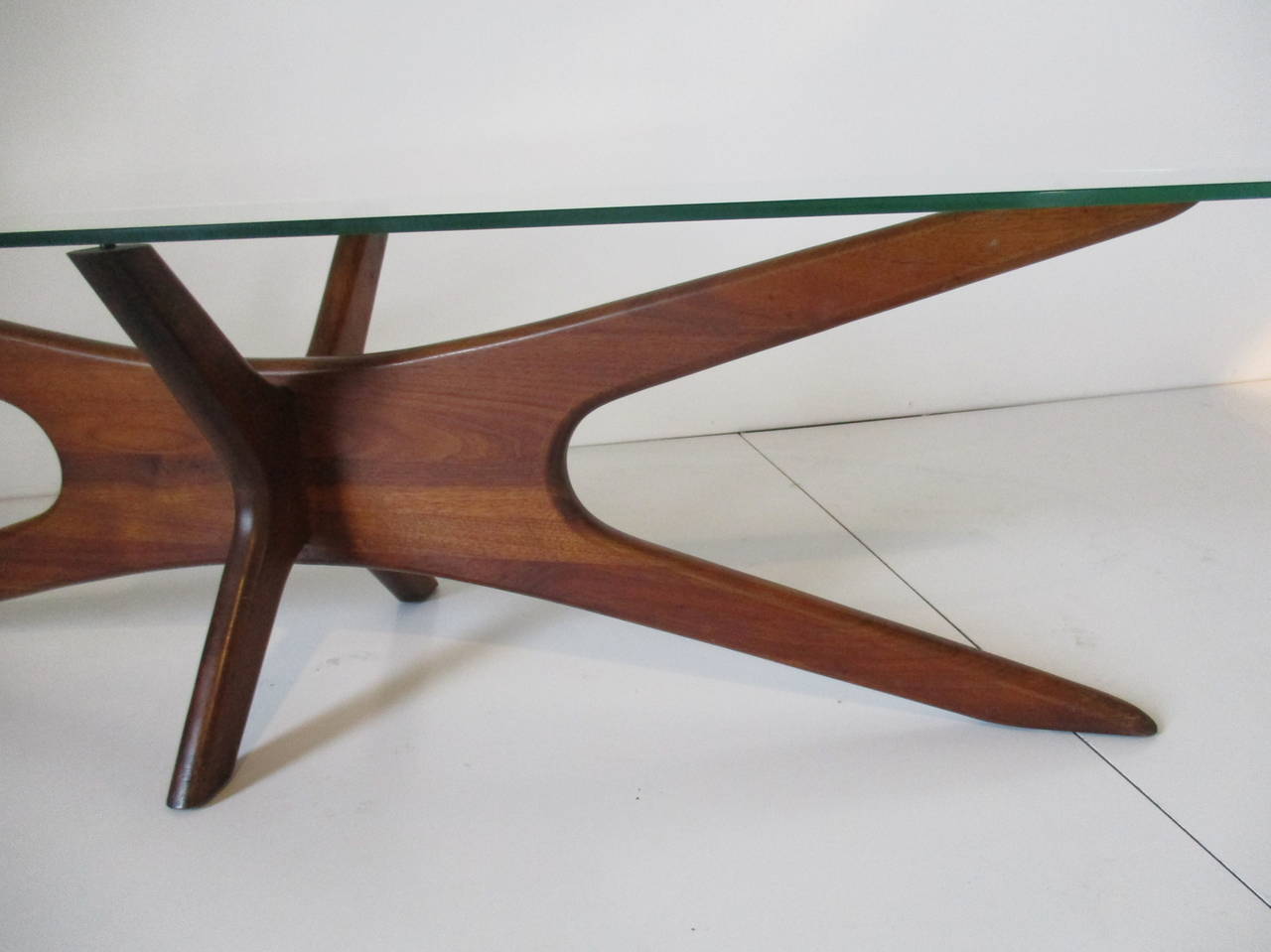 A sculptural solid walnut based jacks coffee table with oval glass top in the style of Kagan.