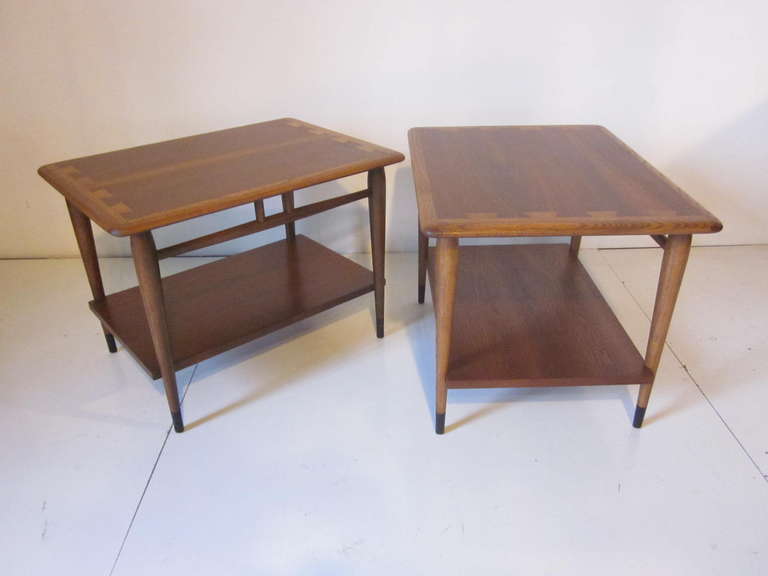 A pair of walnut side tables with dovetailed designed tops and lower shelve sitting on dark leg ends, manufactured by the Lane Furniture company.