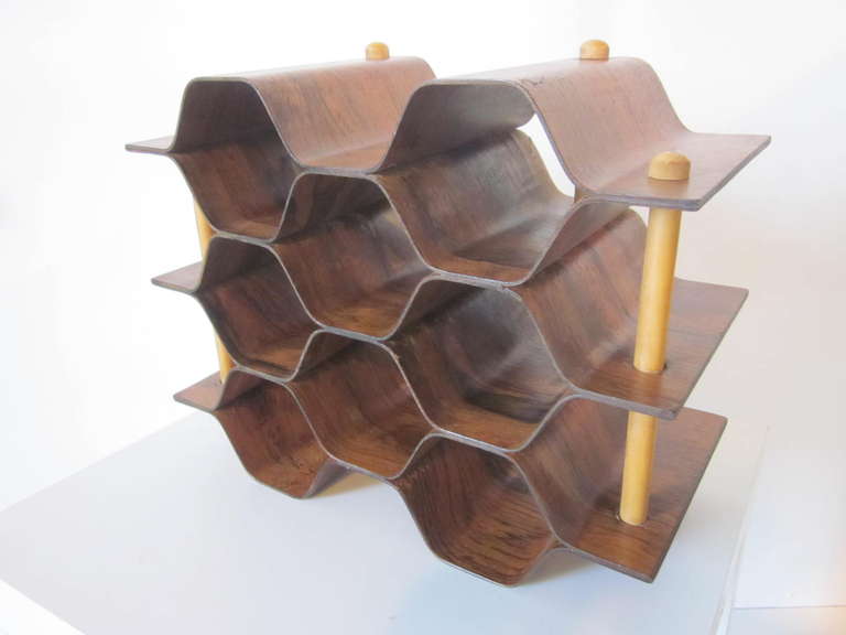 A bentwood wine rack formed from dark and rich Brazilian rosewood with lighter wood rods running through it making a sculptural contrast. The rack can be used on it ends or sides depending on your space.