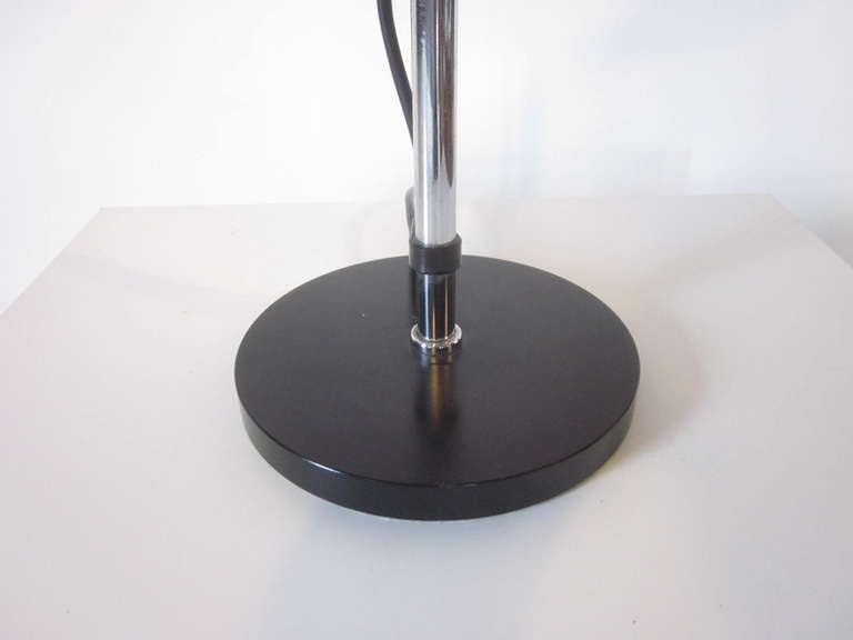 A Mid Century table lamp with red linen shade ,black metal base and chrome rod that the lamp shade can adjust on to varying heights , with a floating lamp cord and lamp cord holder. Manufactured by the Hanseatic Furniture companies Staff / Standard