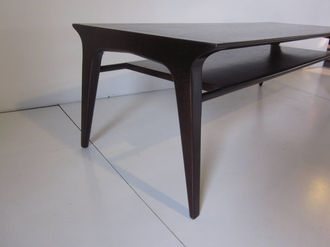 A dark and rich ebony toned coffee table with lower second shelve with great simple lines manufactured by the Drexel Furniture Company.