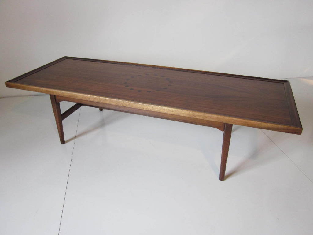 A dark and rich walnut coffee table with raised edge,inlaid  rosewood center design sitting on matching stretchers and legs.Manufactured by the Drexel Furniture company for their Declaration Line.