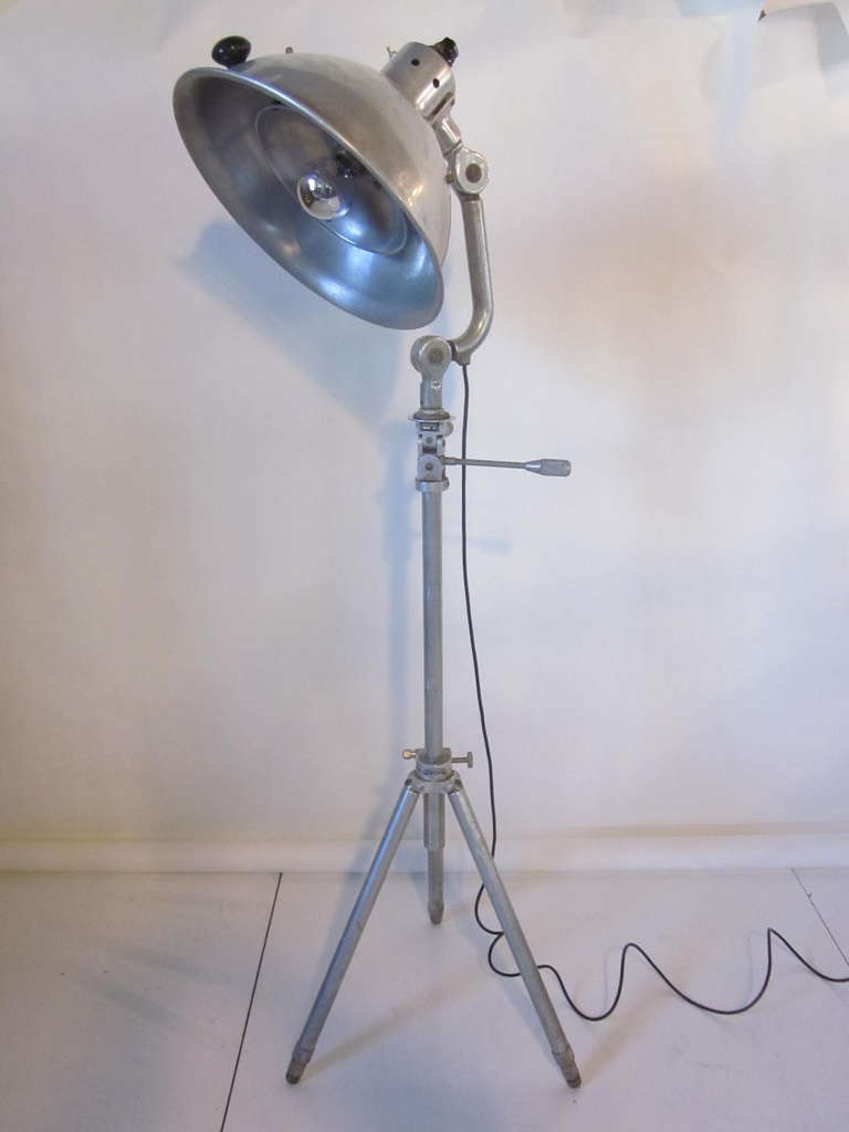 A Machine Age aluminum Industrial floor lamp with a fully adjustable shade, neck, staff and tri-pod legs, retains the manufactures metal tag  C.M.Marchioni company.