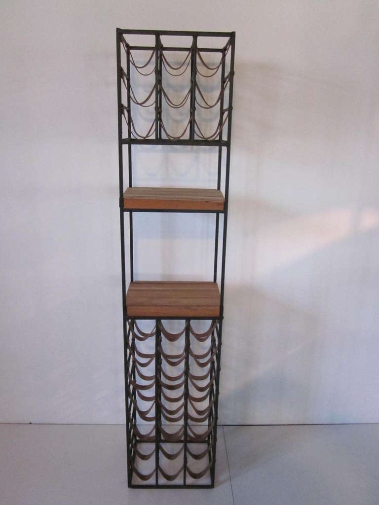 A thirty bottle wine rack made of wrought iron with leather wine straps and two butcher block shelves for the bar area.