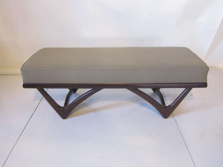 A dark sculptural wood framed bench with deep cushioned top in a medium taupe contract fabric. Manufactured by Craft Associates .