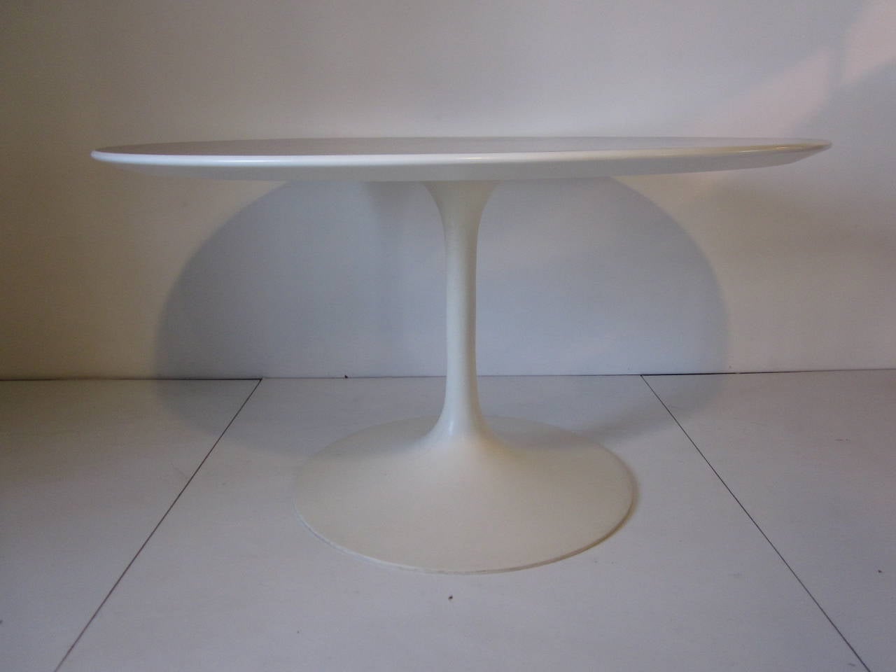 A Saarinen tulip dining table with well grained walnut top, beveled edge and a tulip metal base in a satin white, manufactured by Knoll International.