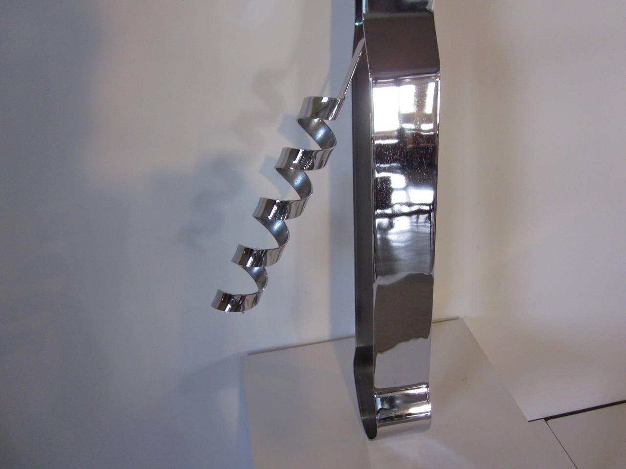 An oversized monumental chrome-plated steel bottle opener with retractable cork screw with welded mounting brackets on the reverse side to hang on any wall. Manufactured by Curtis Jere.