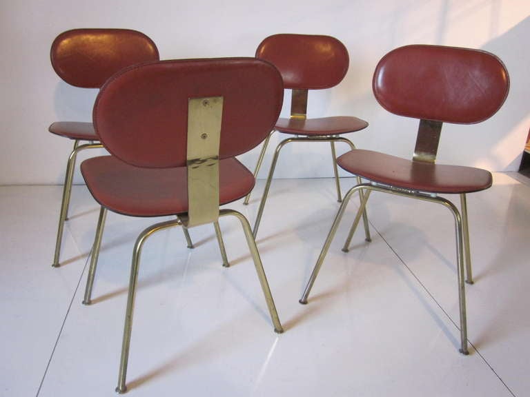 A set of four brass and heavy leather dining chairs,the seat back and bottoms are done in belting leather with the legs and chair spine in brass.
