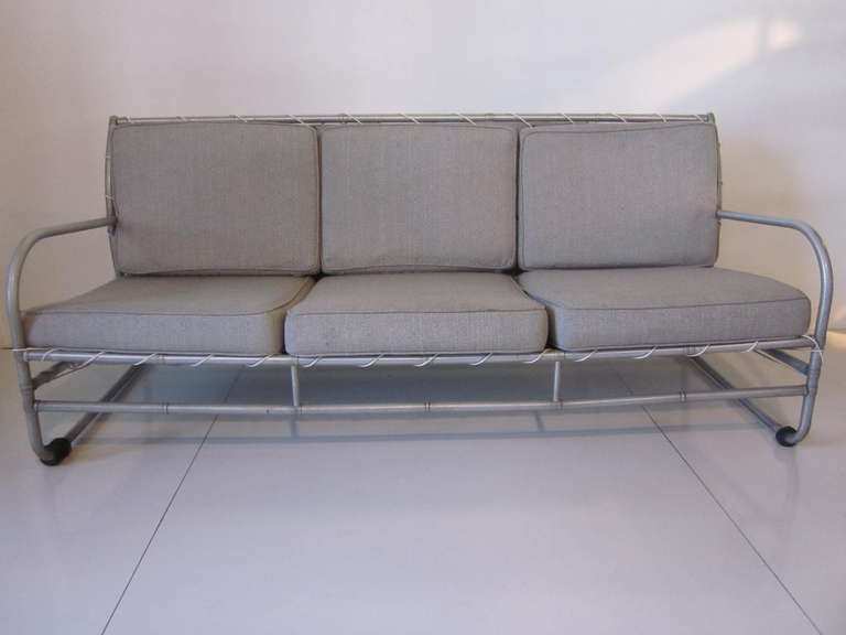 A anodized tubular aluminum terrace settee with laced and fabric back, six cushions and rubber feet. Made in the 30's this rare and hard to find sofa has extreme bends which during the period was quite an amazing manufacturing feat. Perfect for the