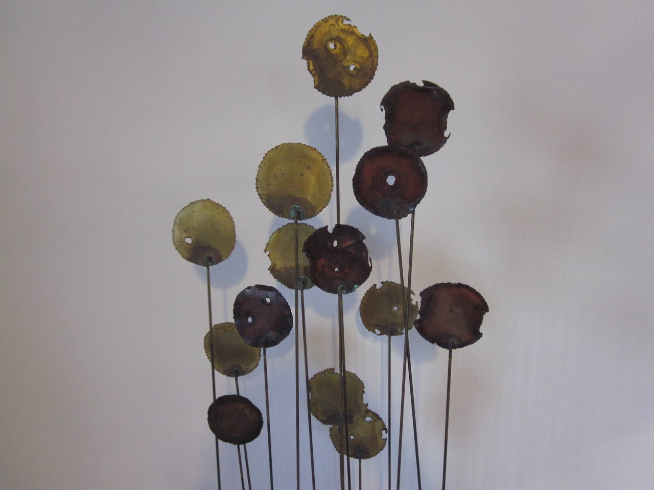 A Kinetic floor sculpture in the manner of Curtis Jere with 14 torch cut and welded medallions floating on long brass rods mounted on a metal multiple legged base.