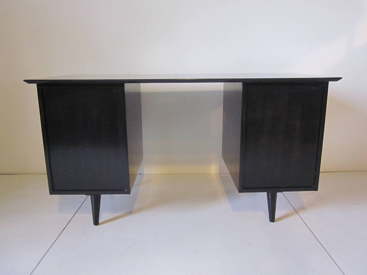 A McCobb pedestal desk in a translucent ebony finish with file drawer, four smaller drawers, put out writing surface and brass pulls. Manufactured by the Winchendon Furniture Company.