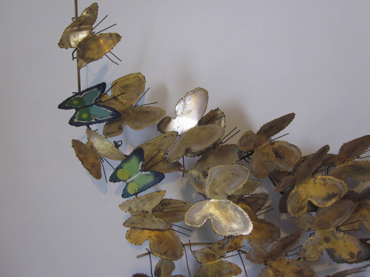 A brass and enameled butterfly wall sculpture with torch cut and welded butterfly designs with blue and orange toned metal enamel butterflies for detail. Signed and dated Curtis Jere, 1968.