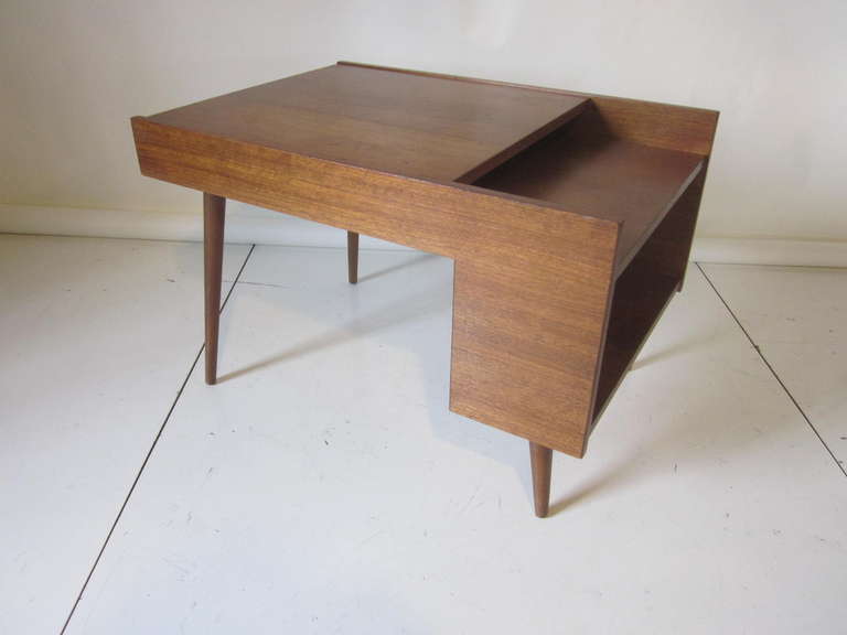 A walnut side table with a great Mid Century modern architectural vibe , storage shelves to one side and conical legs for support, manufactured by Glenn of California and an early design by Milo Baughman.