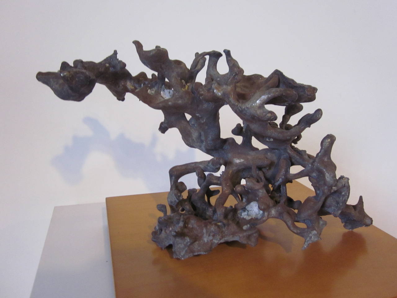 A free form organic contemporary steel sculpture in the manner of Claire Falkenstein with flowing movement very typical of her works, sitting on a wooden base. 